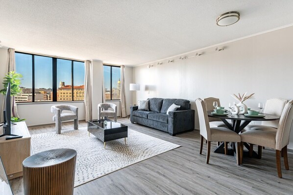 A modern living room with a sofa, chairs, a coffee table, and a dining area with a table and chairs.