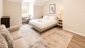 Une chambre à coucher avec un lit, un bureau, une chaise, une lampe et un tableau au mur.