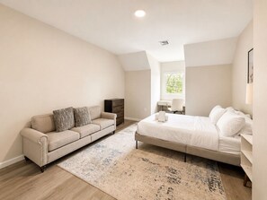 Quarto com cama, sofá, escrivaninha e janela.