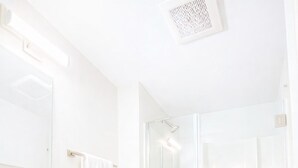 A modern bathroom with a white vanity, a toilet, and a glass-enclosed shower.