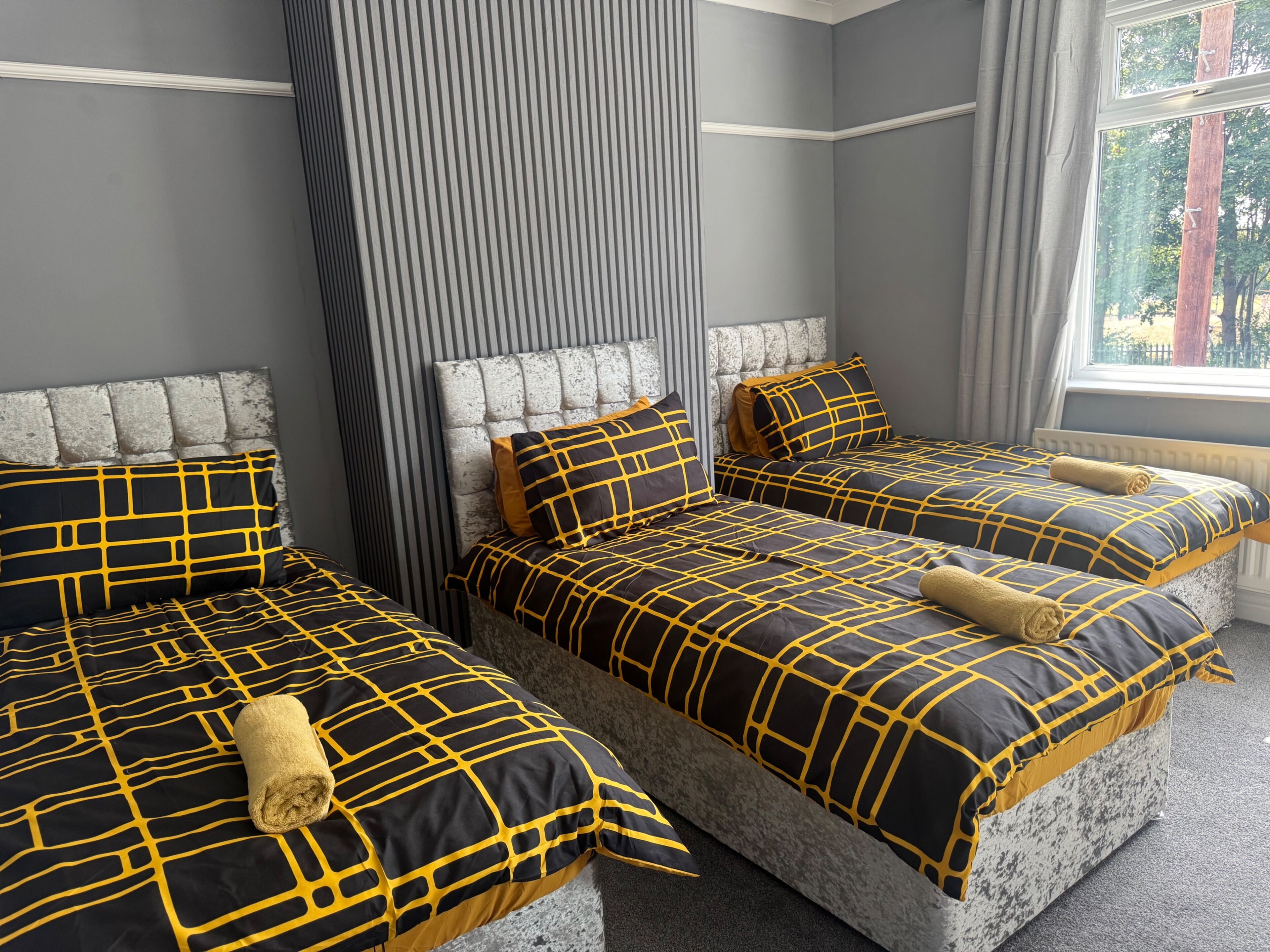 A hotel room with three beds, each with a headboard and matching bedding.