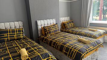 A hotel room with three beds, each with a headboard and matching bedding.