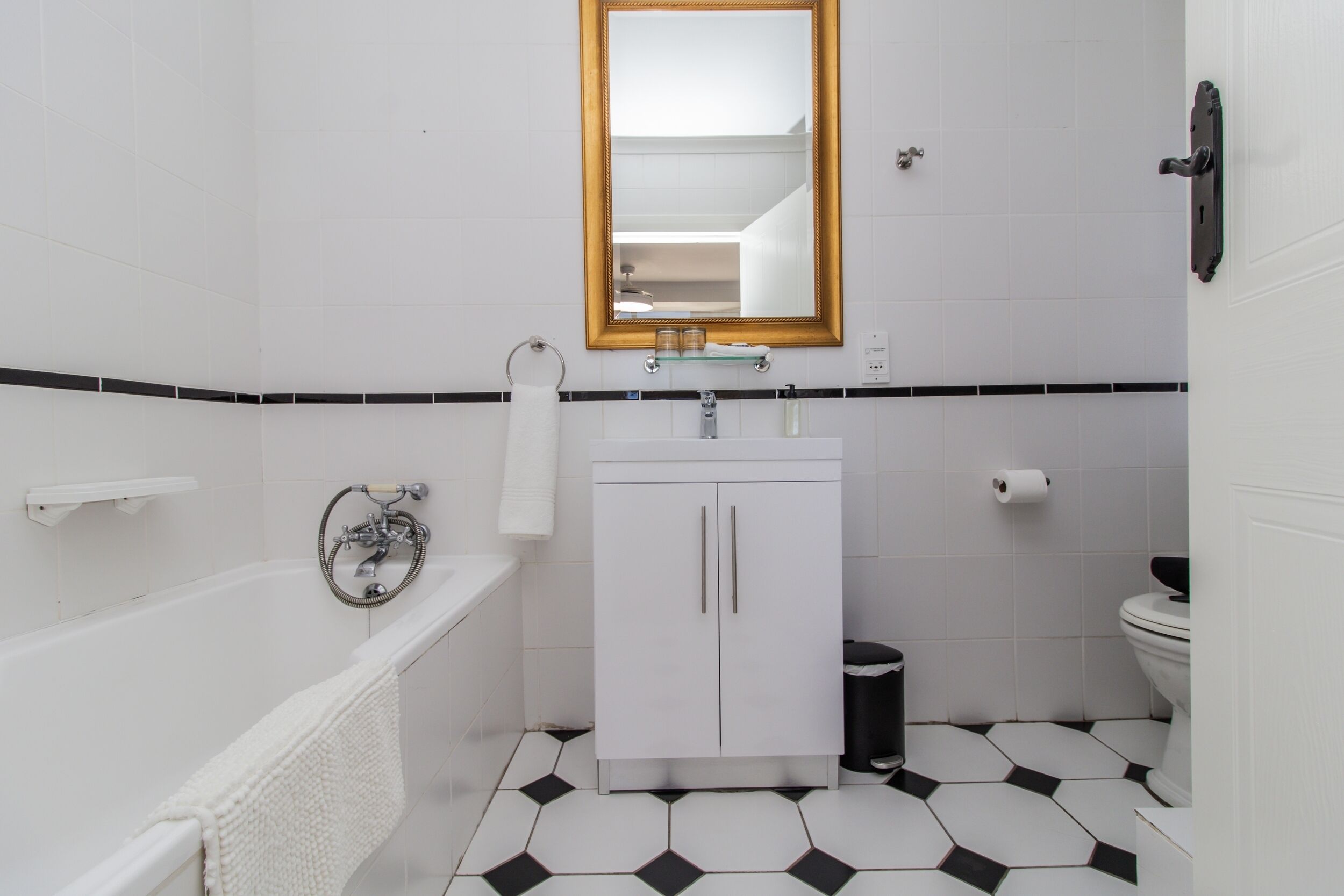 Een badkamer met een wit bad, een wastafel met een spiegel erboven en een toilet.