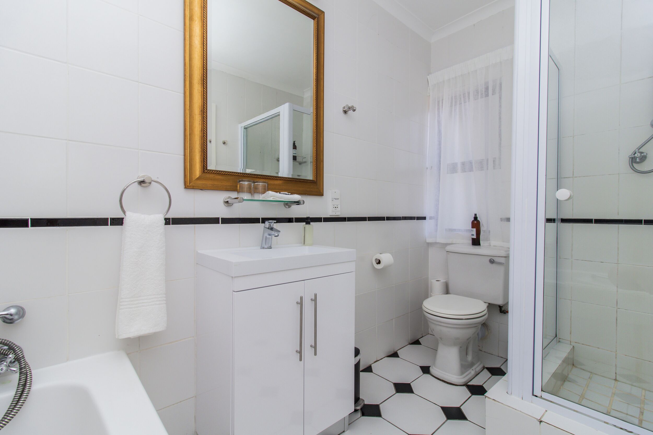 Ein Badezimmer mit weißem Waschbecken, Spiegel, Toilette und Dusche.