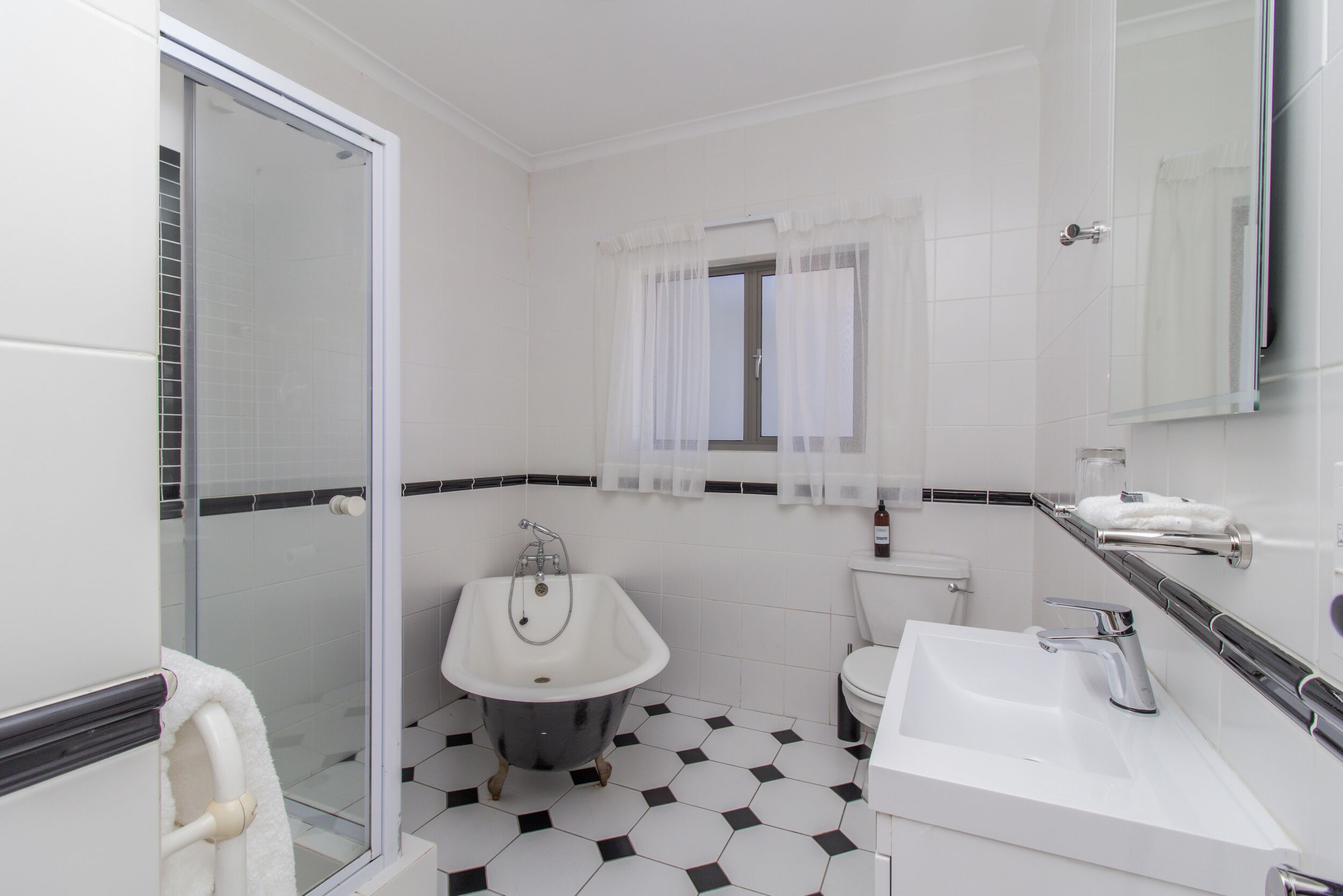 Un baño con cabina de ducha de vidrio, una bañera independiente, un lavabo y un inodoro.