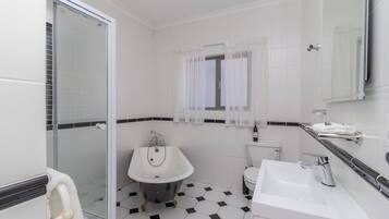 Un baño con cabina de ducha de vidrio, una bañera independiente, un lavabo y un inodoro.