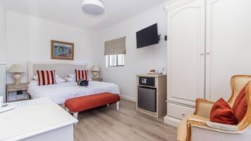 Hotelkamer met een bed, bureau, stoel, kast, televisie en raam.