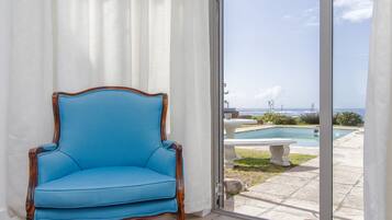 Een blauwe fauteuil bij een schuifpui met uitzicht op een zwembad en een terras.