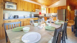 Eine Küche mit Holzausstattung, einem Esstisch mit Geschirr und Gläsern sowie einem Kühlschrank.