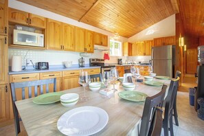 Eine Küche mit Holzausstattung, einem Esstisch mit Geschirr und Gläsern sowie einem Kühlschrank.