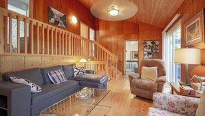 A wooden interior with a sofa, armchair, and a glass coffee table. - Four Mile Memories - Three Bedroom Cottage, Sleeps 6 (Kawartha Lakes)