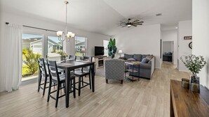 Un amplio salón con mesa de comedor, sillas, sofá y televisor.