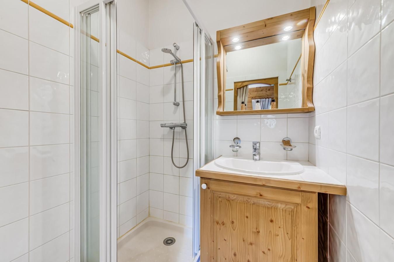 Une salle de bain avec une douche, un lavabo et un meuble-lavabo en bois.