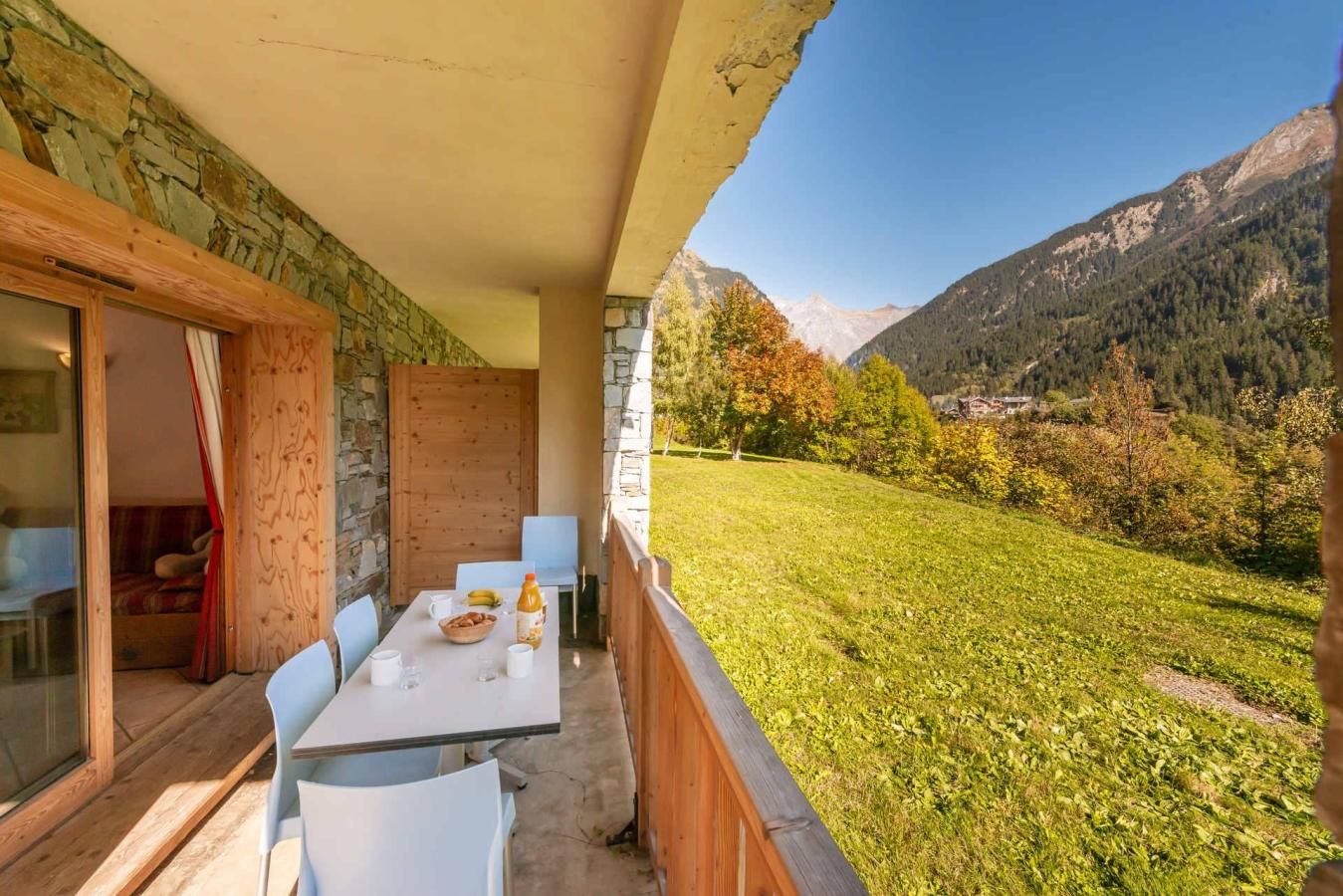 A balcony with a table set for dining, overlooking a lush green landscape and mountains.
