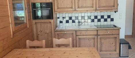 A wooden kitchen with a tiled backsplash, a stove, and cabinets.