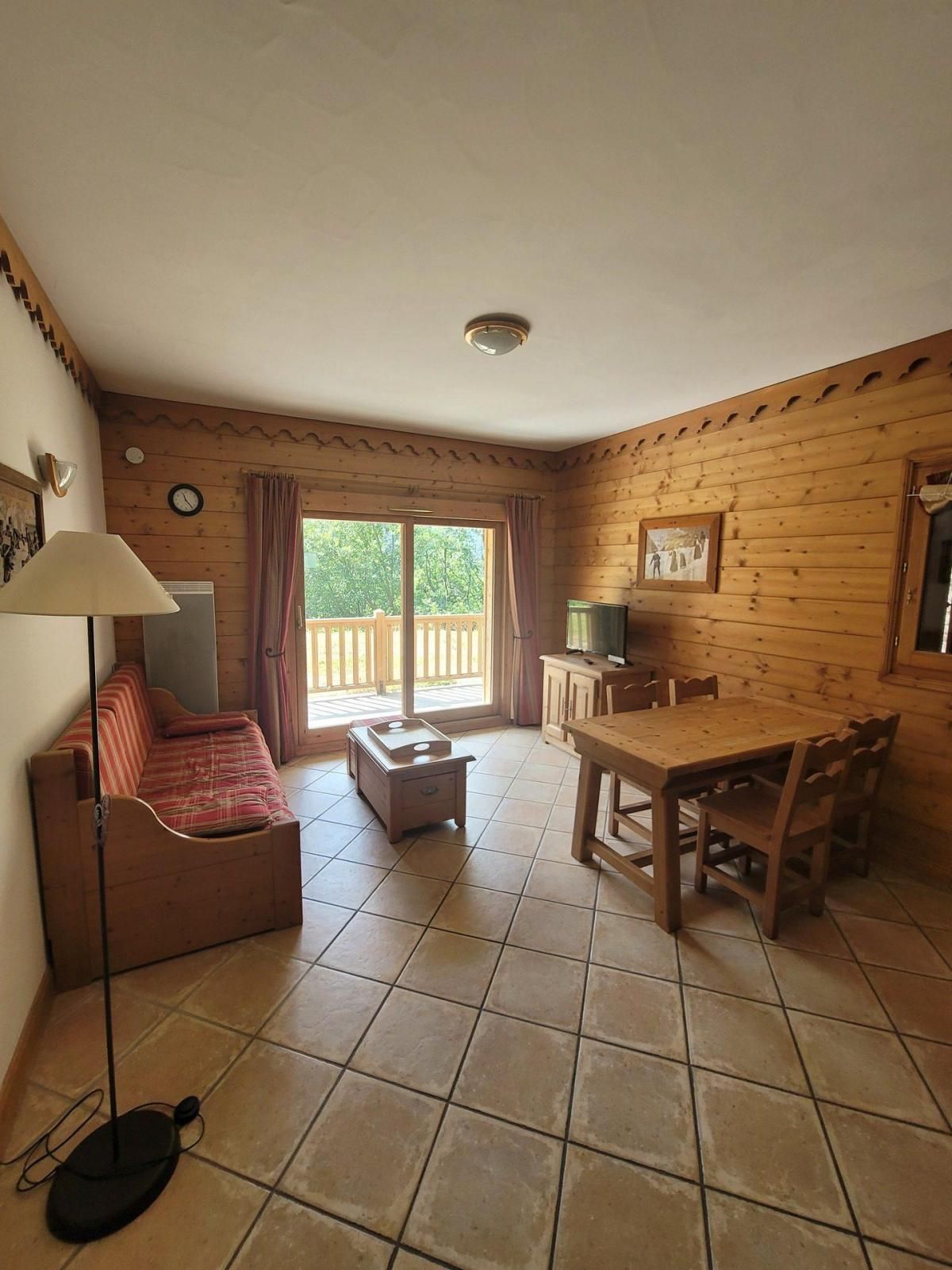 Una habitación acogedora con sofá, una mesa de comedor con sillas, televisión y ventana con vistas al verdor.