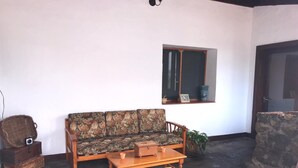 Un salon comprenant un canapé, une table basse en bois, un banc en pierre et une fenêtre ornée d’un cadre.