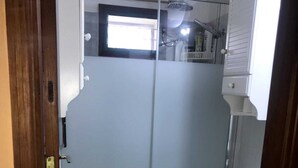 Une salle de bain avec des toilettes, un espace douche et un tapis vert sur le sol.