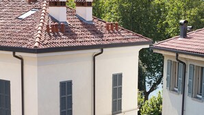 A multi-story building with a tiled roof, multiple chimneys, and a street sign indicating 'MILANO 50'. - Royal Suite - Lake Como (Lecco)