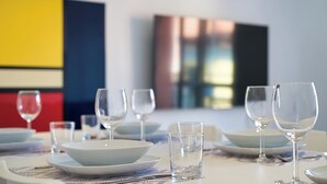 A dining table set with white plates, bowls, and clear glasses, with a modern abstract painting in the background. - Royal Suite - Lake Como (Lecco)