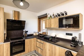 A modern kitchen with wooden cabinetry, a built-in oven, a microwave, and a coffee machine.