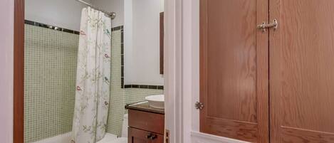 A bathroom with a bathtub, toilet, and a wooden cabinet.