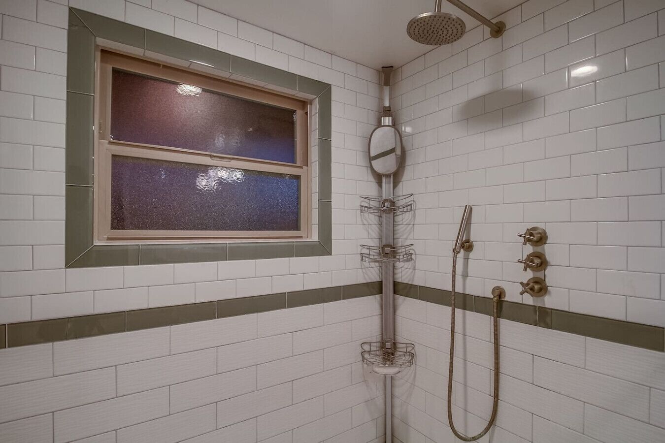 Une douche avec une fenêtre, un porte-serviettes et un pommeau de douche.