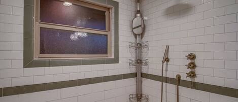 Une douche avec une fenêtre, un porte-serviettes et un pommeau de douche.