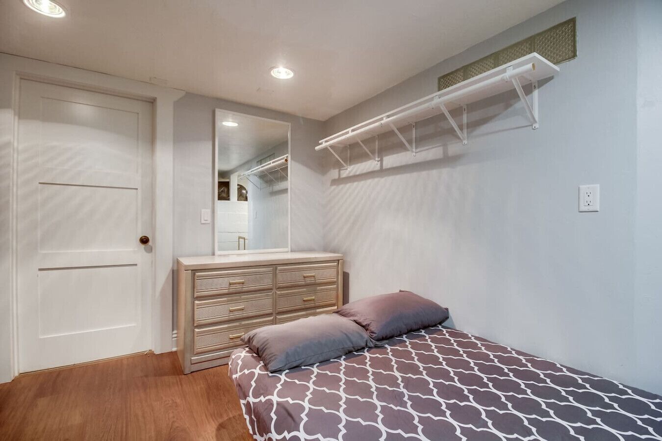 Un dormitorio con cama, cómoda, espejo y armario.
