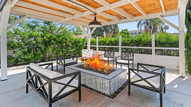 A covered outdoor patio with a fire pit, seating area, and a pergola structure. - San Diego Gem-Charming 4BR Home (San Diego)