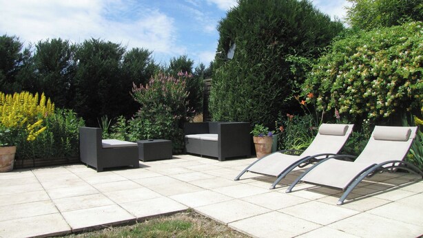 Eine Terrasss mit Sitzgelegenheit, bestehend aus einer Couch und zwei Lounge-Sesseln.