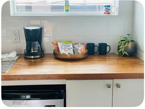 Een keuken met een koffiezetapparaat, een schaal met snacks en een bloempot.
