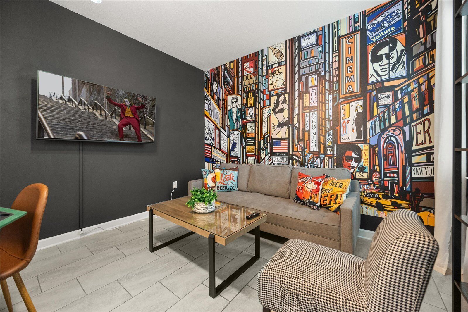 Un salon moderne avec un canapé gris, une table basse et une fresque colorée sur le mur.