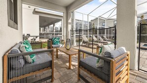 A covered outdoor seating area with a table, two sofas, and a grill. - 681-Sticks (Kissimmee)