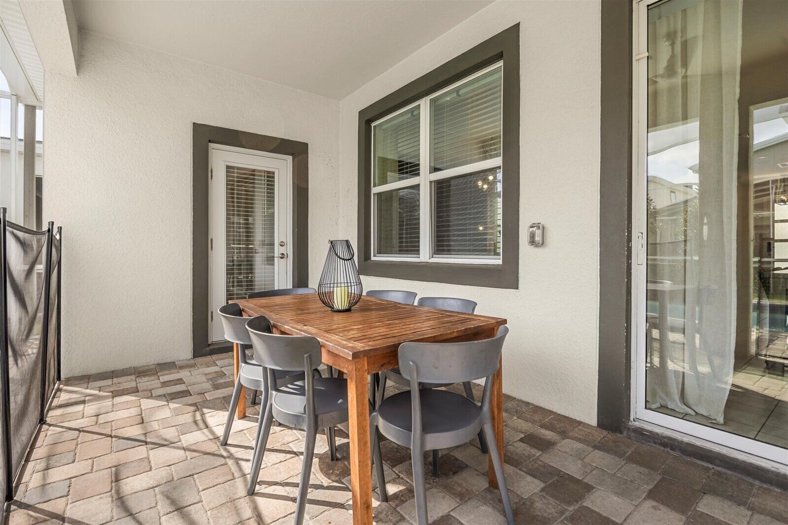 A dining area with a wooden table and six chairs, a vase, and a window with blinds.