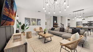 A spacious living room with a sofa, coffee table, and chairs, a kitchen area, and a dining space. - 681-Sticks (Kissimmee)