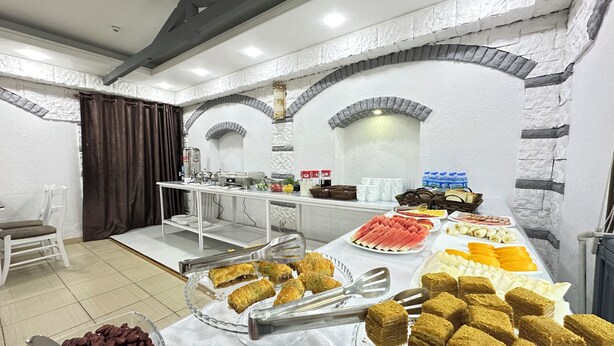 A buffet setup with various food items and utensils. - Grand Zamin Hotel (Tashkent)