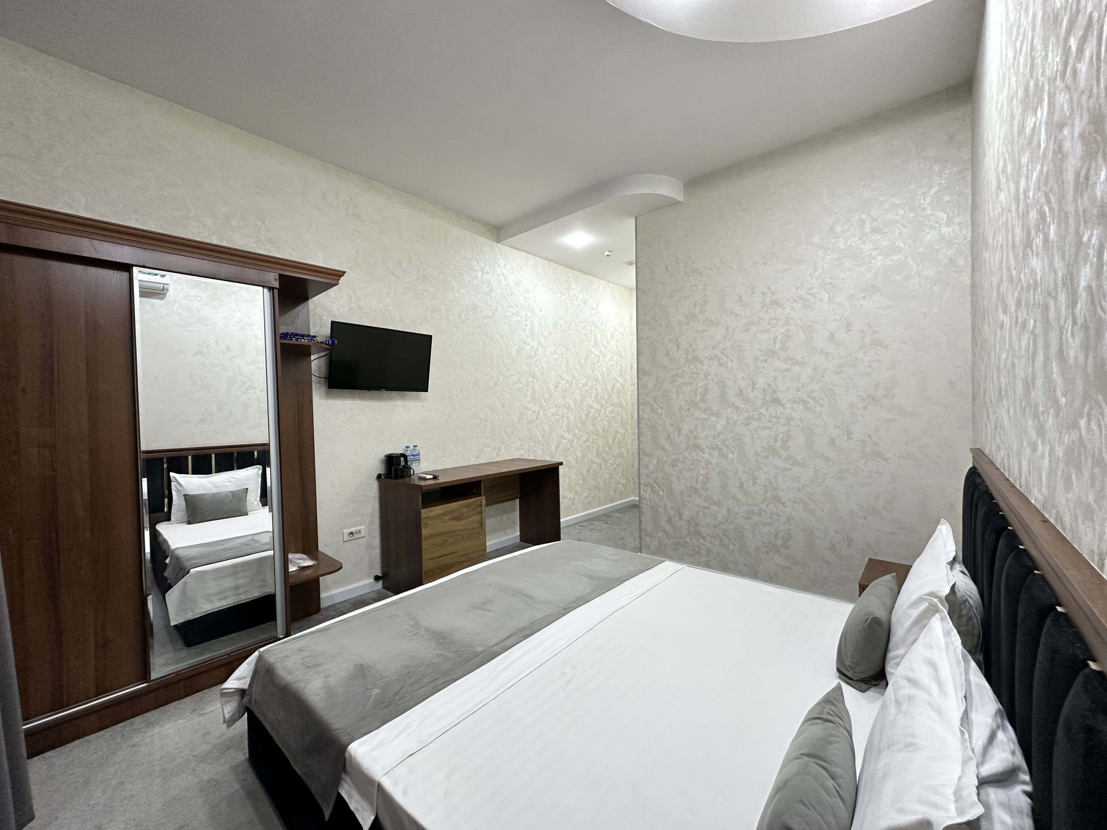 A hotel room with a bed, a desk, a TV, and a wardrobe.