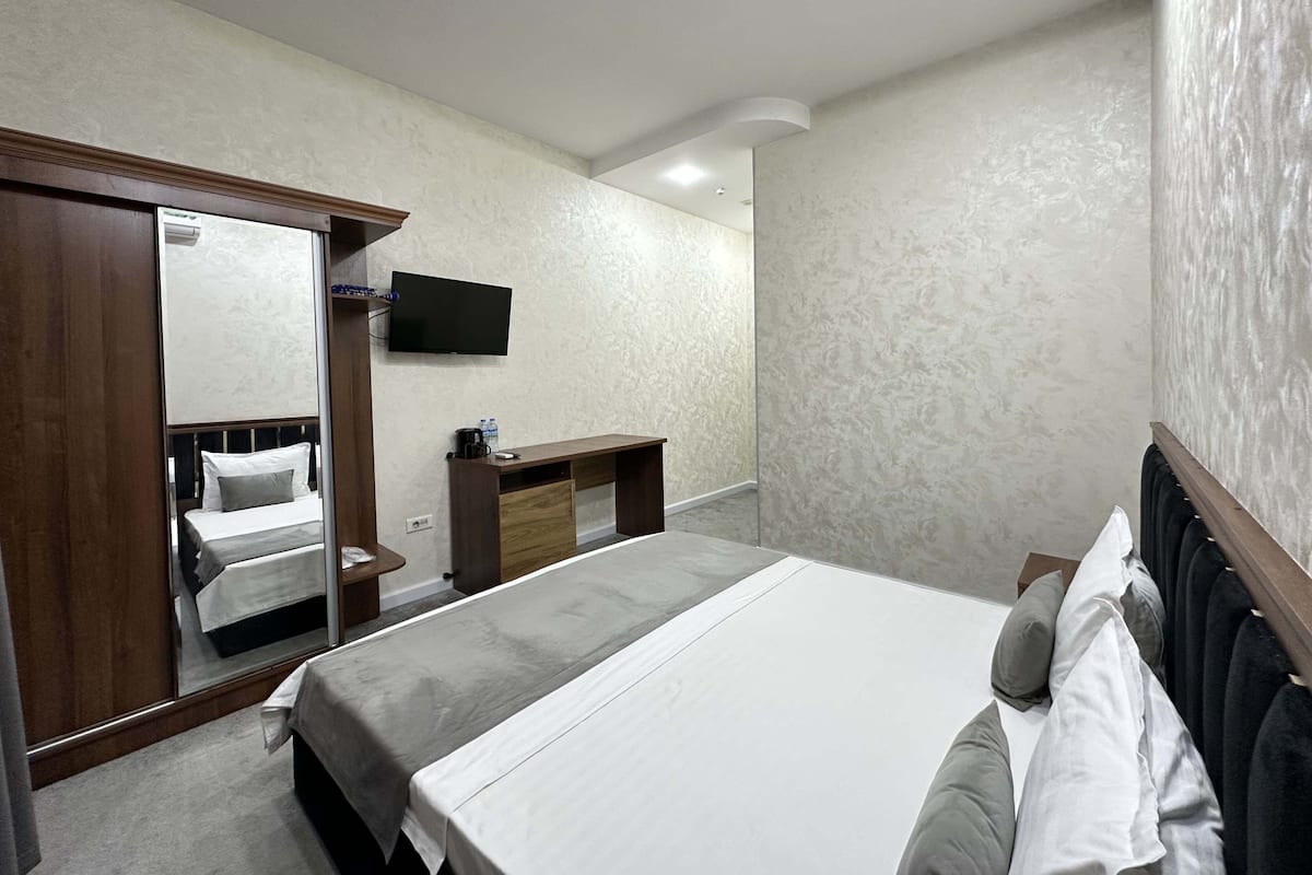 Une chambre d’hôtel avec un lit, un bureau, une télévision et une armoire.