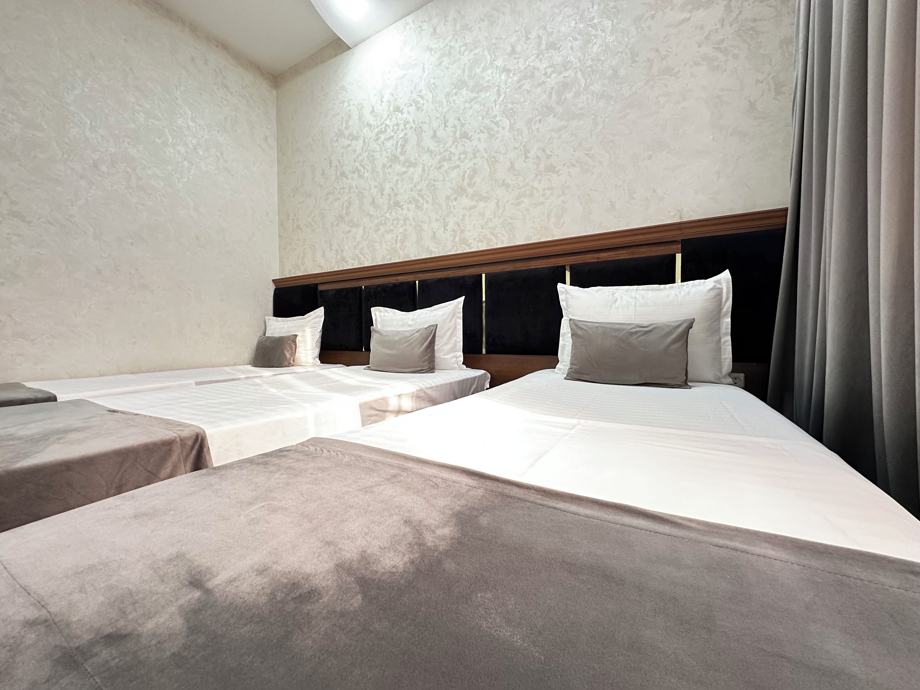 Une chambre d’hôtel avec deux lits simples, une tête de lit en bois et une petite table de chevet.