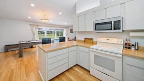 A modern kitchen with white cabinetry, a built-in microwave, and a stove.