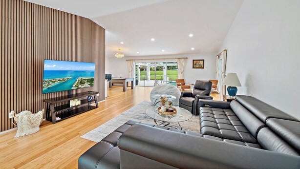 A modern living room with a large TV, leather sofa, and a wooden accent wall.