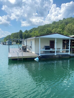 A lakeside cabin with a dock, outdoor seating, and a covered porch. - 2-bedroom house boat in charming Speedwell with AC (Speedwell)
