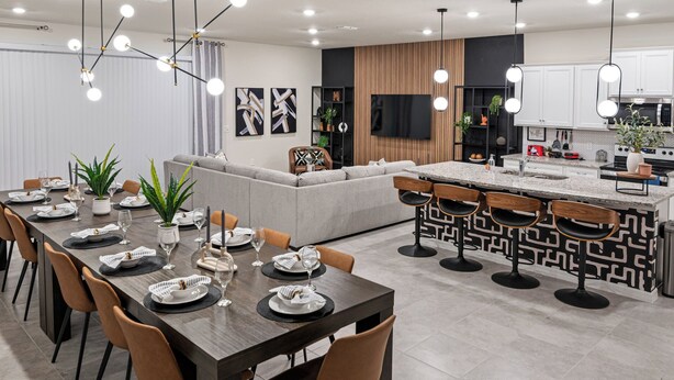 A modern kitchen with white cabinets, a built-in oven, and a dining area with a long table and chairs.