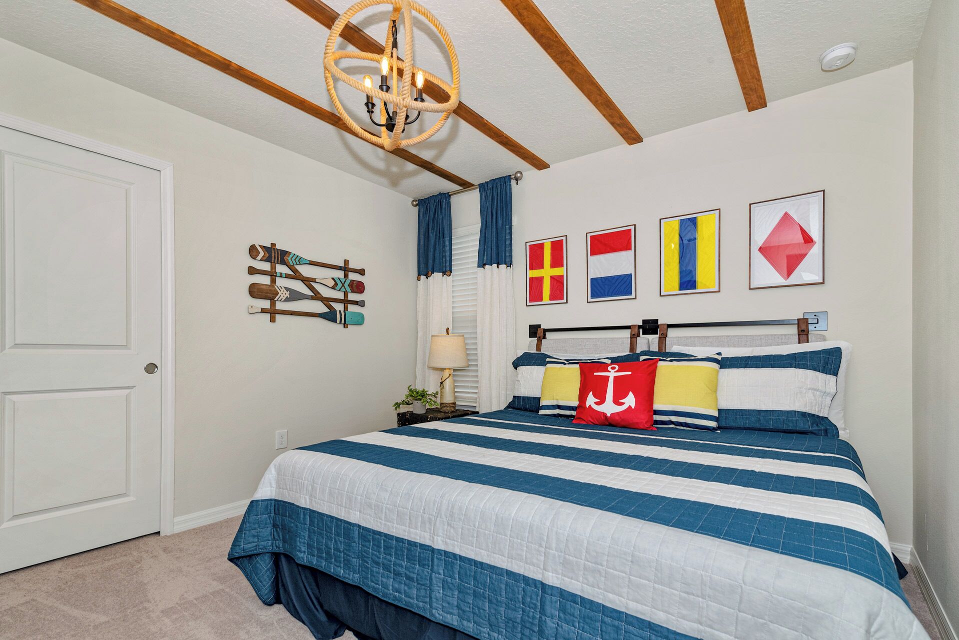 A bedroom with a bed, a chandelier, flags on the wall, and a door.