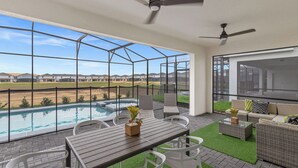 A balcony with a pool, outdoor seating, and a view of a residential area.