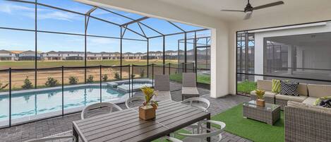 A balcony with a pool, outdoor seating, and a view of a residential area.