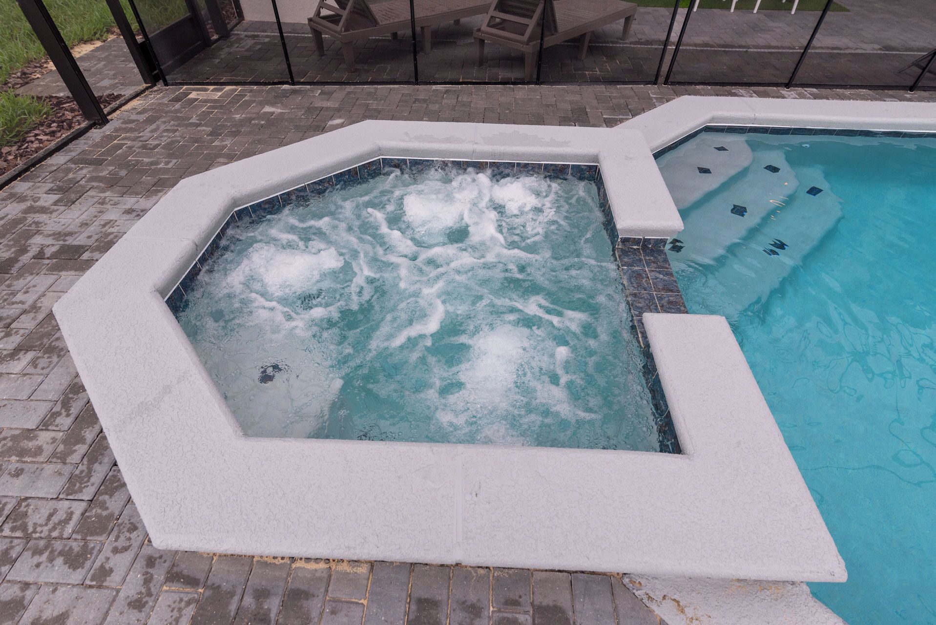 Een whirlpool met betegelde binnenkant en een omliggend zwembad.