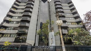 Un moderno edificio de gran altura con varios balcones y una fachada central de vidrio.