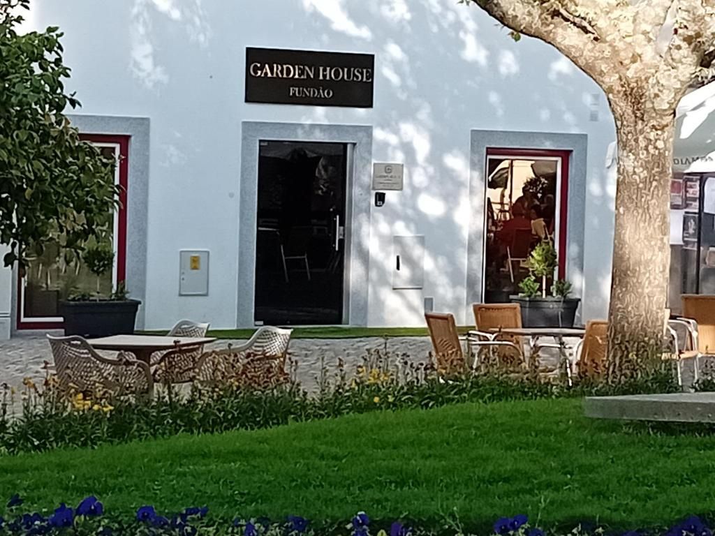 A building labeled 'Garden House Fundão' with outdoor seating and a tree.